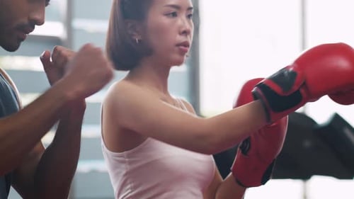 Sporty woman doing boxing exercises with personal trainer at the gym.