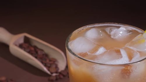 Close-up of a Cappuccino with Ice cubes in a tall Glass against a black background