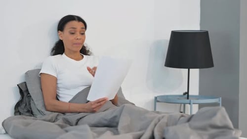 Woman Reads Paper in Bed and Reacts Positively