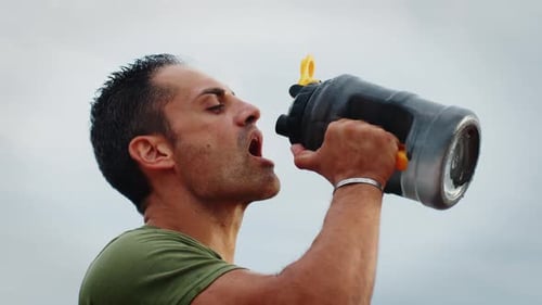 Athlete Quenches His Thirst with Bottles of Water