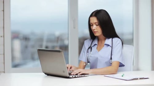 Woman Doctor Typing at Desk With Laptop