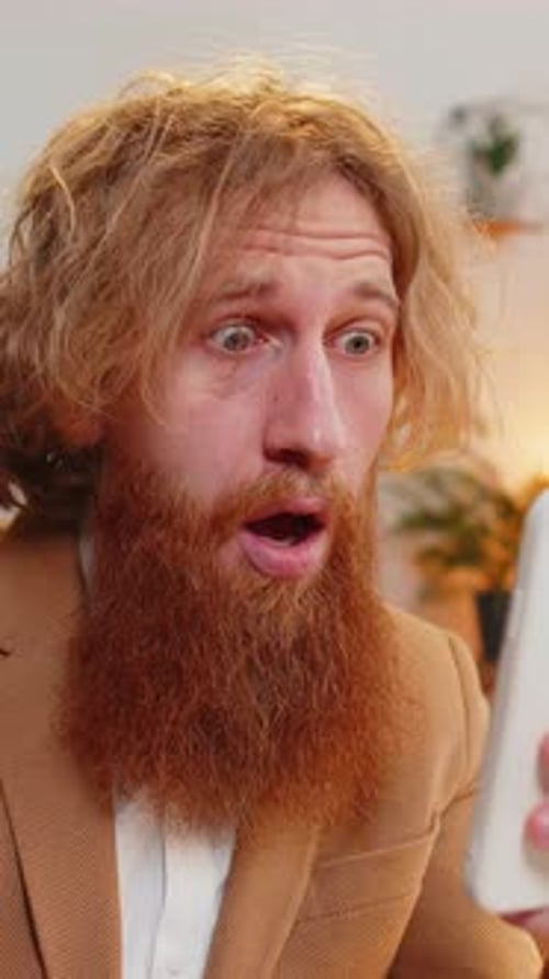 Man looks surprised at his phone screen indoors