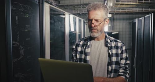 Man With Laptop Working in Server Room