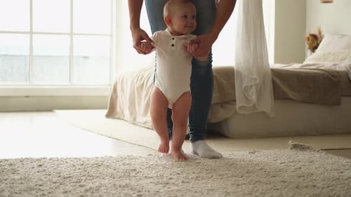 Infant Learning to Walk with Parent in Bedroom