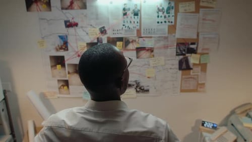 Detective Analyzes Evidence On Crime Board