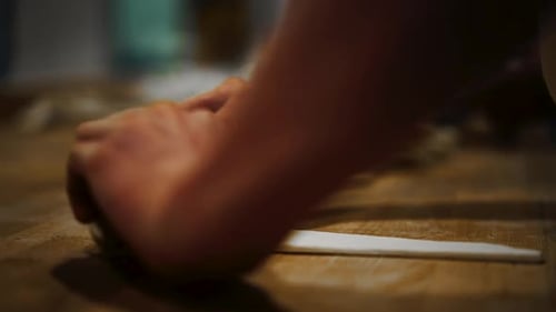 close-up shallow focus shot of baker shaping triangle slab of dough into a croissant by rolling it t