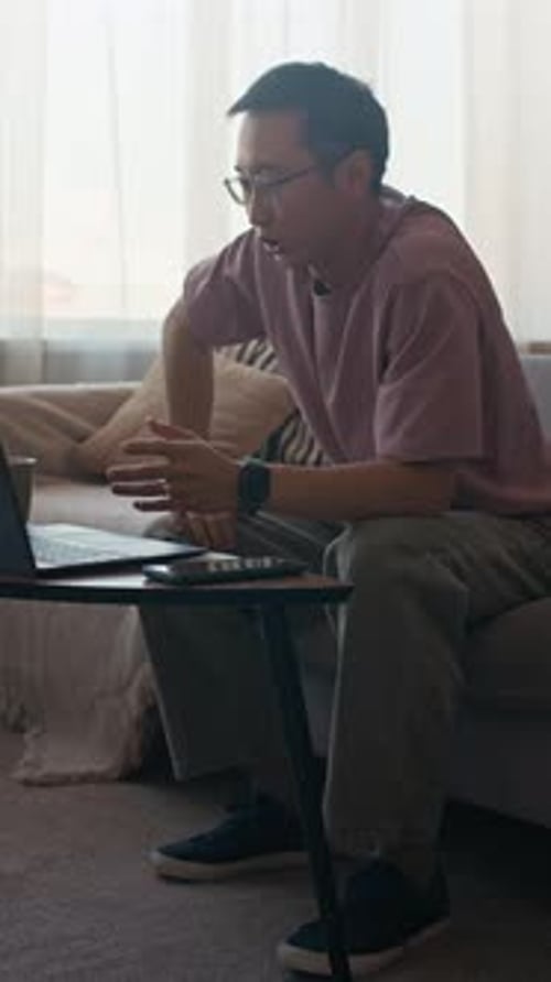 Vertical of Male Manager Talking on Video via Laptop in Home Office