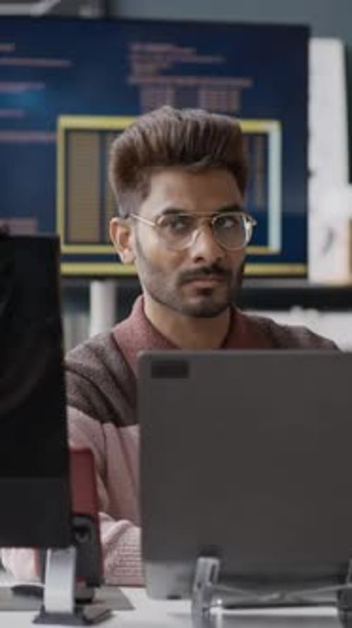 Vertikale Darstellung eines indischen Softwareentwicklers, der im Technologiebüro am Laptop arbeitet