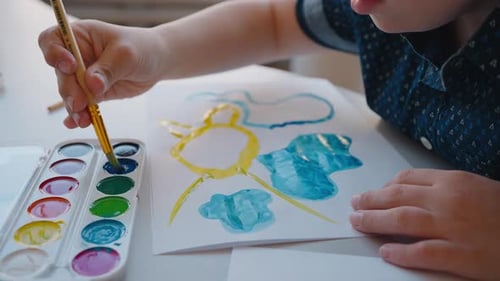 Young Boy Painting Watercolor Art at Table