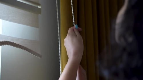 Young woman opening the roller blinds 4K