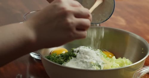 Close Up of a Woman's Hands Adding Flour to All the Other Ingredients to Make Vegetable Pancakes
