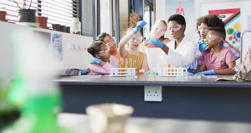 Diverse female teacher and happy schoolchildren having science class in school lab
