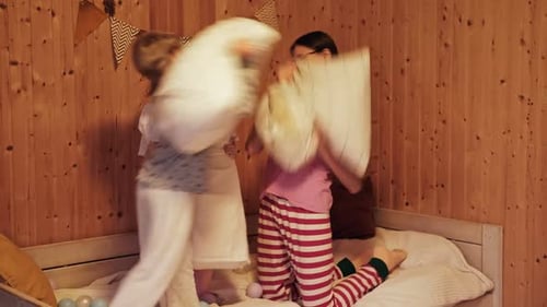 Des enfants sautent sur le lit et se battent avec des oreillers pendant une soirée pyjama, Pillow Fight Dance Party