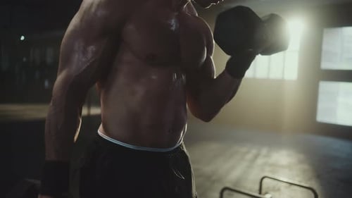 Muscular athlete lifting dumbbells