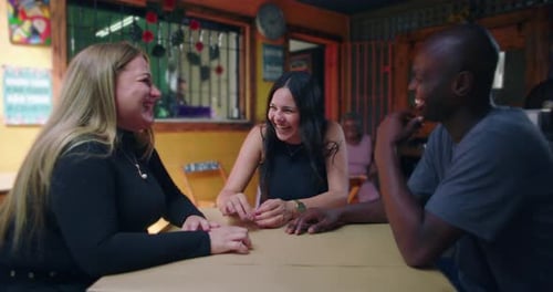 Friends sitting together at small neighborhood café sharing conversation and laughter expressing