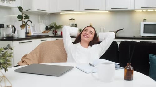 Woman Working on Laptop at Kitchen Table Relaxing