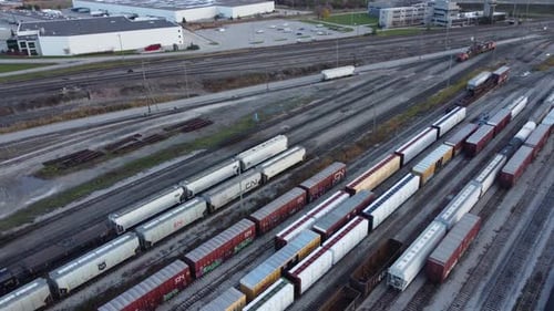 Aerial drone shot as a train drives into station. Trainyard.