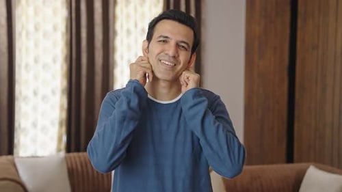 Annoyed Man Plugging Ears Indoors