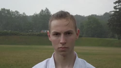Serious Young Man in Karate Gi in Rain