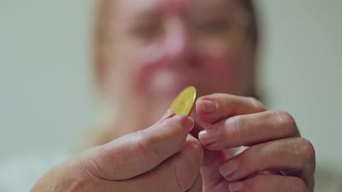 Woman Examining a Gold Bitcoin, Close Up