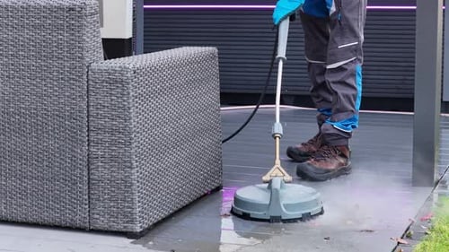 Man Cleaning Gray Patio With Pressure Washer