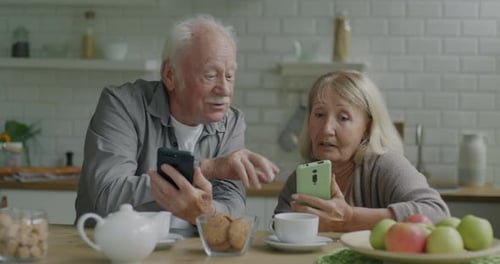 Senior Couple Using Smartphones in Bright Kitchen