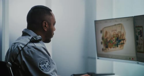 Airport Security Checkpoint TSA Worker Controlling Scanning of Luggage on Computer Monitors