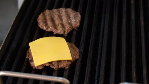 Cheese Being Placed on Burgers on the Grill