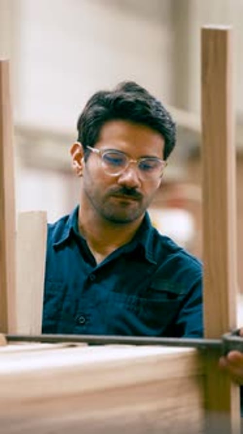 Focused Male Carpenter Assembling Wooden Furniture Frame Vertical
