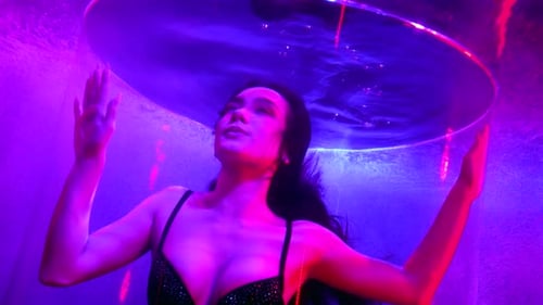 Woman Posing in an Underwater Tank with Vivid Lighting