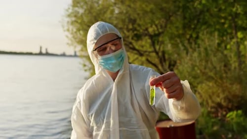 Scientist Holding Sample By Water Investigating River Pollution