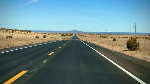 Traveling down the straight open road in Arizona with mountains in the background