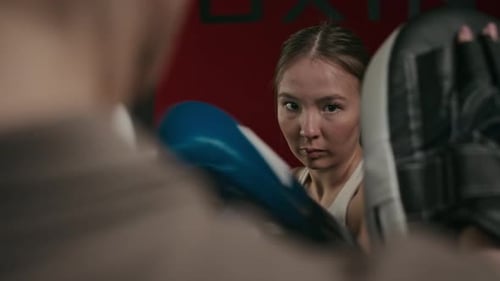 Dedicated Woman Boxing with Trainer in Urban Gym