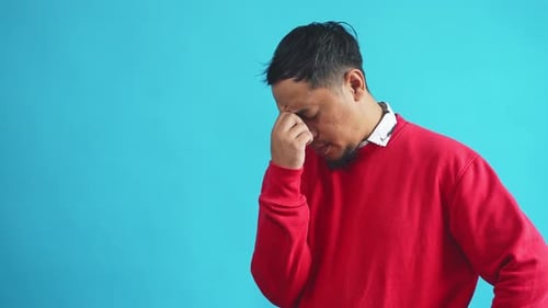 Man Touching Forehead Against Bright Blue Background