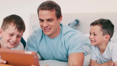 Father and Sons Enjoying Tablet Together on Bed