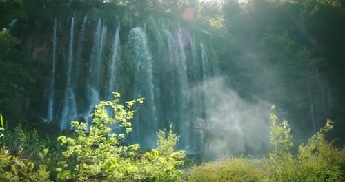 Stunning Waterfall with Water Cascading Down a Rocky Cliff Creating Mist in the Air Lush Greenery