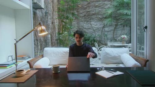 Man Entering Home Office, Sitting on Sofa and Working on Laptop