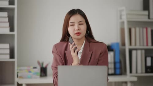 Woman Answering Call While Using Laptop in Office