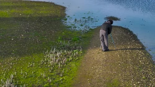 Photographer Sets Up Camera Next to a Grassy Lake