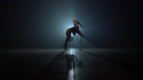 Hermosa chica gimnasta haciendo ejercicios de flexión hacia atrás en segundo plano. Mujer atlética estirándose