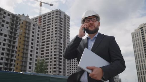 Engineer in Suit and Hard Hat Talking on Phone at Construction Site