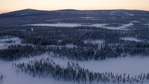 Aerial view looking down over Scandinavian woodland landscape tilt up reveal snow covered mountain r