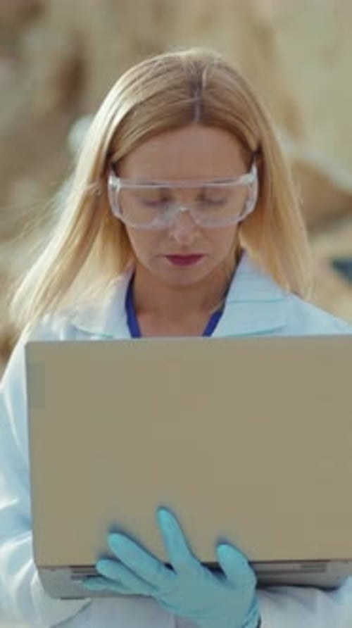 Woman Scientist Holding Laptop Wearing Safety Glasses