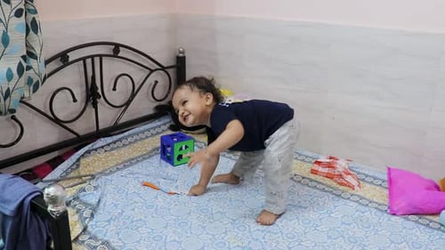cute toddler baby boy trying to stand for the first time at bed at home