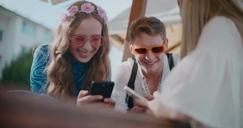 Three Friends Laughing Looking at Smartphones Together