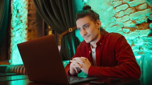 Un travailleur indépendant est assis à une table de restaurant ou de café et travaille sur un ordinateur portable