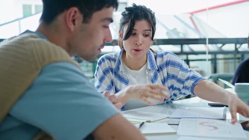 Young Woman Discussing Business Report with Coworker in the Office