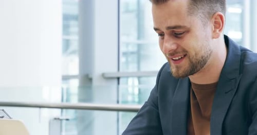 4k video footage of a handsome young businessman working on his laptop in the office