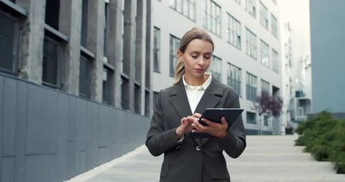 Close Up of Beautiful Young Busy Female Manager Holding Tablet While Walking Outdoors Near Business