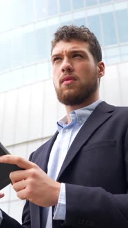 Porträt eines männlichen Geschäftsmannes oder Unternehmers außerhalb des Büros mit einem Tablet in einem Glasgebäude